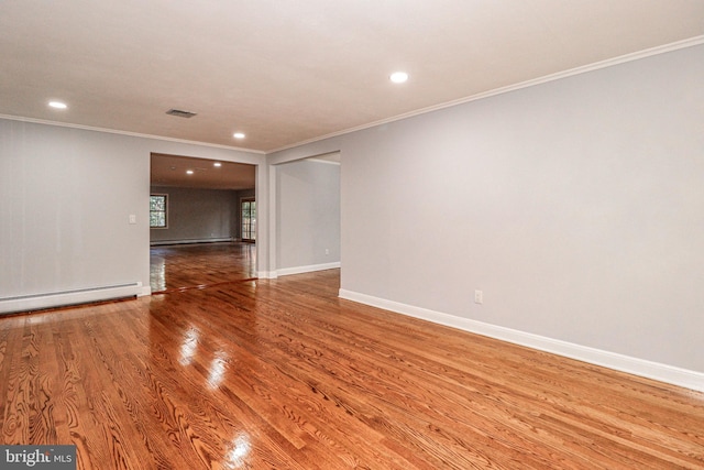 empty room featuring a baseboard heating unit, crown molding, and wood-type flooring