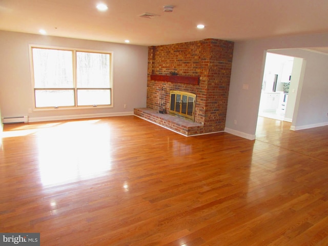 unfurnished living room with wood-type flooring, a fireplace, and a baseboard radiator