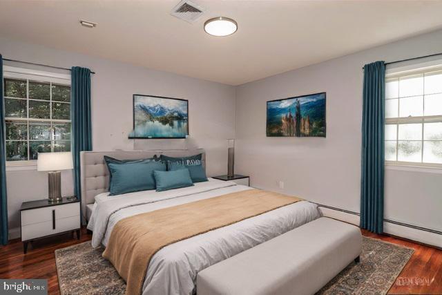 bedroom with baseboard heating and dark wood-type flooring