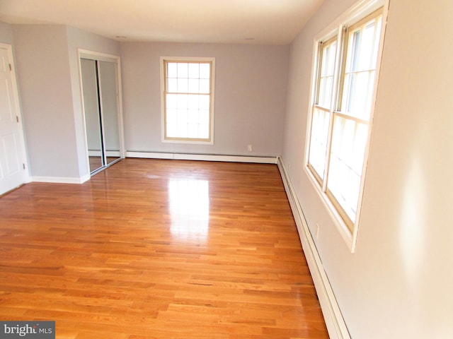 unfurnished room with a baseboard radiator and light hardwood / wood-style flooring