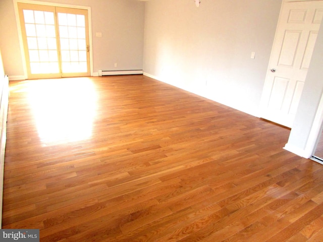 unfurnished room featuring a baseboard heating unit and wood-type flooring