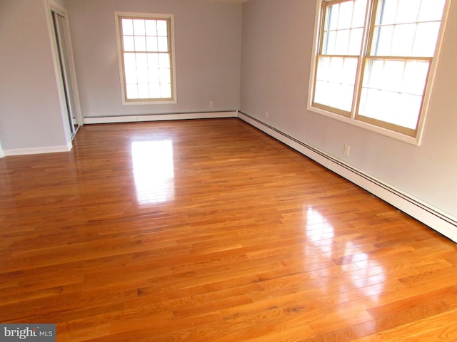 empty room featuring a baseboard heating unit and light hardwood / wood-style flooring