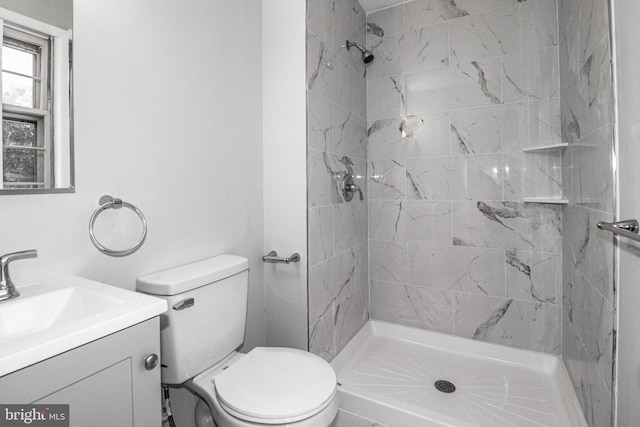 bathroom with vanity, tiled shower, and toilet