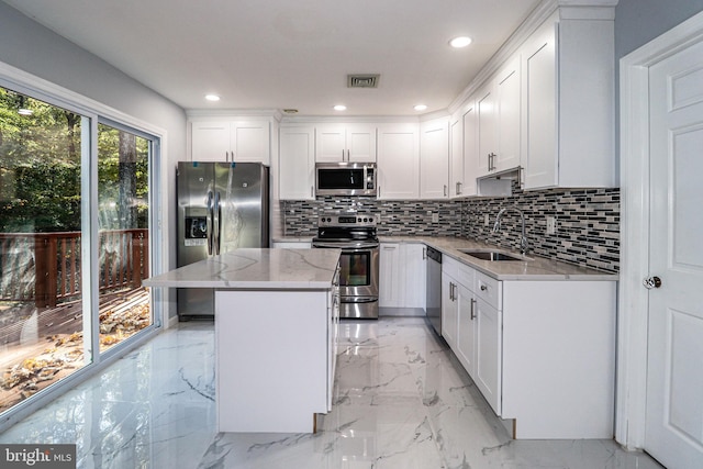 kitchen with appliances with stainless steel finishes, sink, light stone counters, and white cabinetry