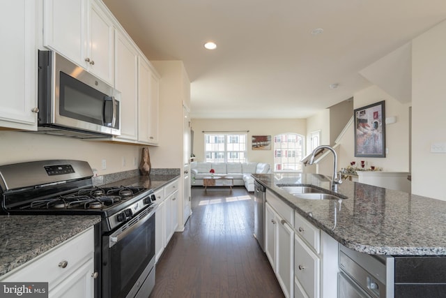 kitchen with sink, a kitchen island with sink, white cabinetry, and stainless steel appliances