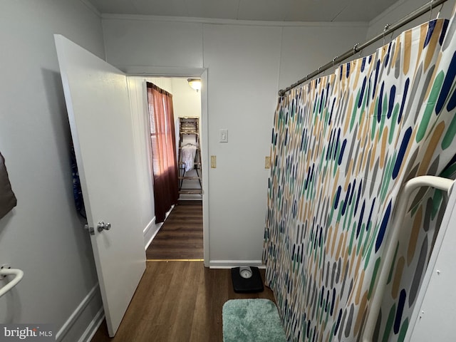 hallway with dark wood-type flooring, crown molding, and baseboards