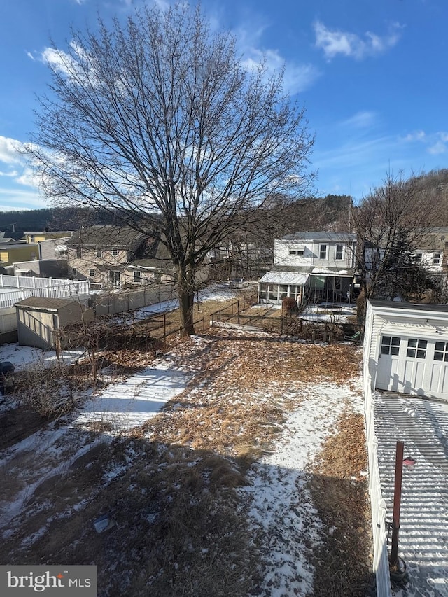 snowy yard featuring a residential view and fence