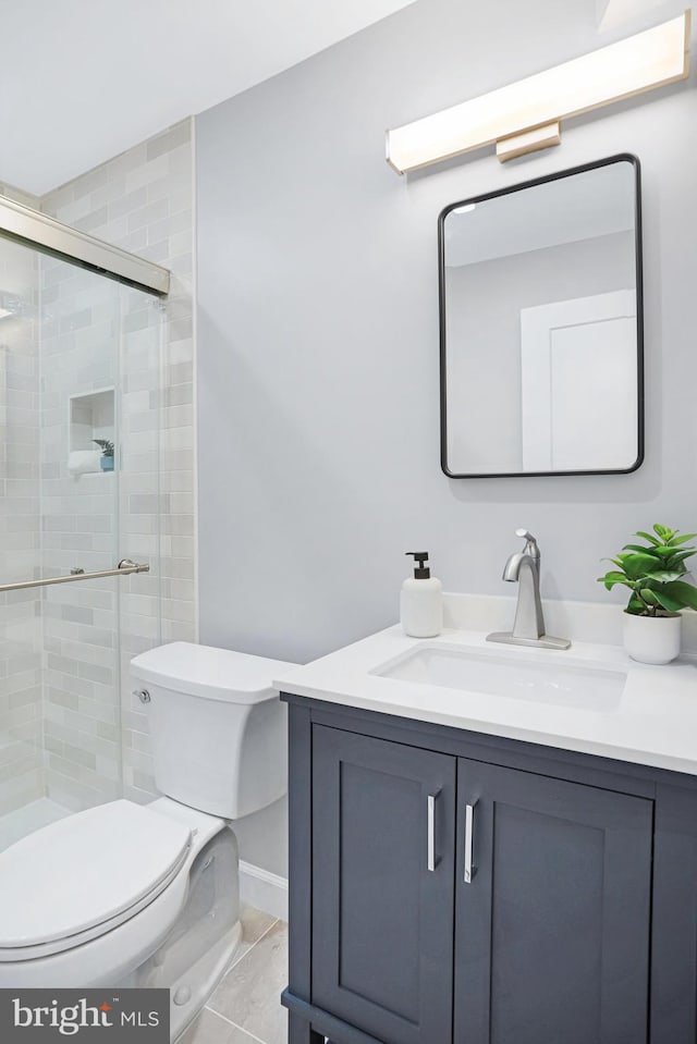 bathroom with toilet, a shower with door, and vanity