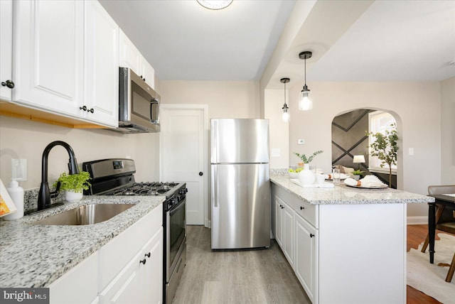 kitchen with appliances with stainless steel finishes, sink, white cabinetry, and light stone counters