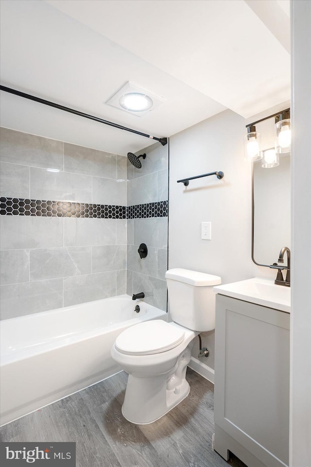 full bathroom with hardwood / wood-style floors, toilet, vanity, and tiled shower / bath