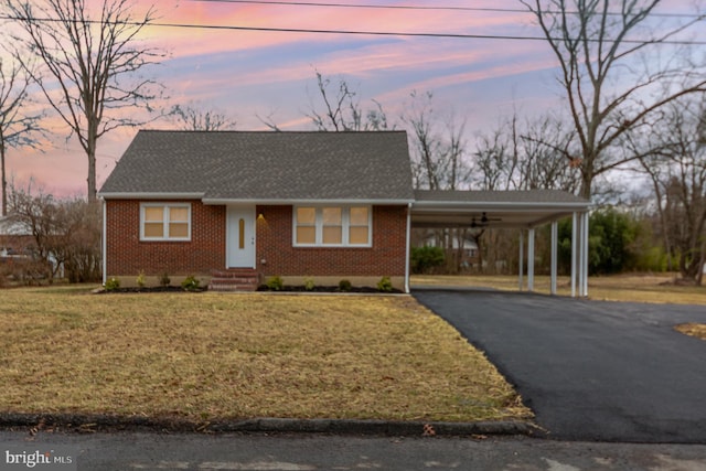 view of front of home with a yard, an attached carport, brick siding, and driveway