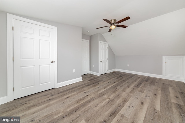 additional living space with a ceiling fan, vaulted ceiling, baseboards, and wood finished floors