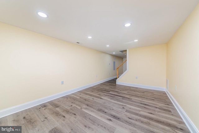 finished below grade area with light wood-type flooring, stairway, baseboards, and recessed lighting