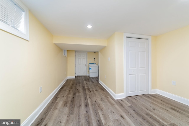 corridor with wood finished floors, washer / dryer, and baseboards