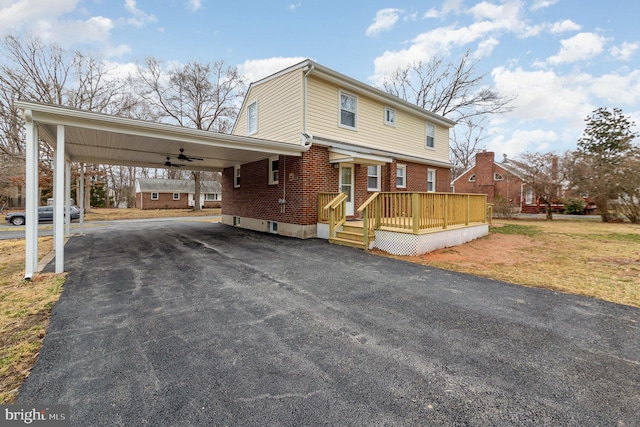 view of front of home featuring driveway, an attached carport, a wooden deck, and brick siding