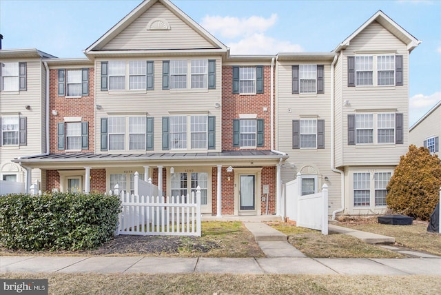 townhome / multi-family property featuring brick siding, a standing seam roof, and fence