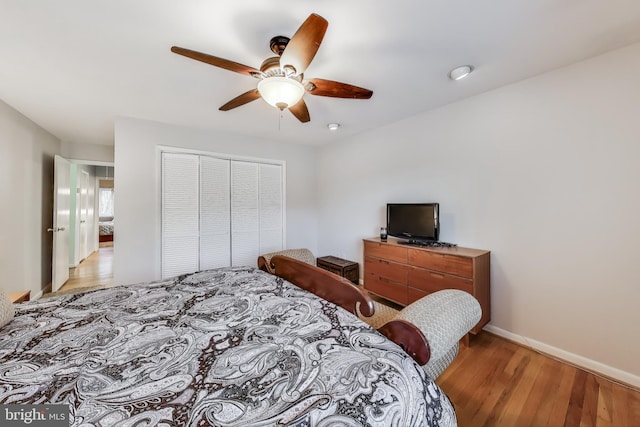 bedroom with light wood-style flooring, baseboards, ceiling fan, and a closet