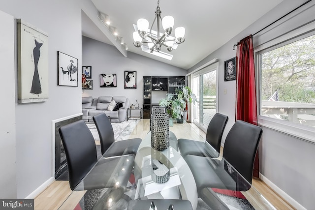 dining area featuring lofted ceiling, baseboards, a notable chandelier, and light wood finished floors