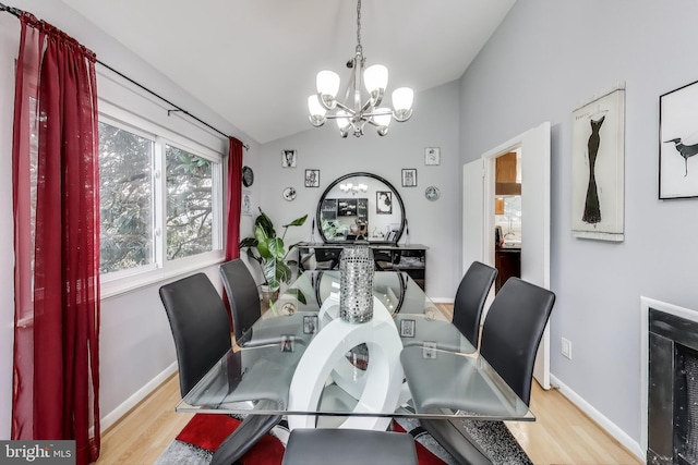 dining room featuring lofted ceiling, light wood finished floors, baseboards, and an inviting chandelier