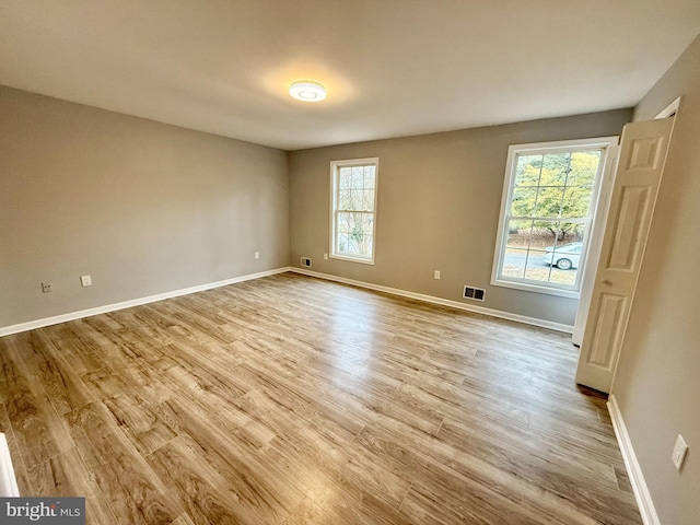 empty room with visible vents, baseboards, and wood finished floors