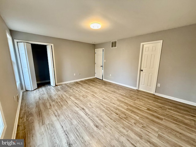 unfurnished bedroom with visible vents, baseboards, and wood finished floors