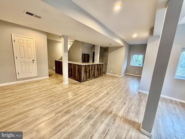 unfurnished living room featuring visible vents, baseboards, and light wood-type flooring