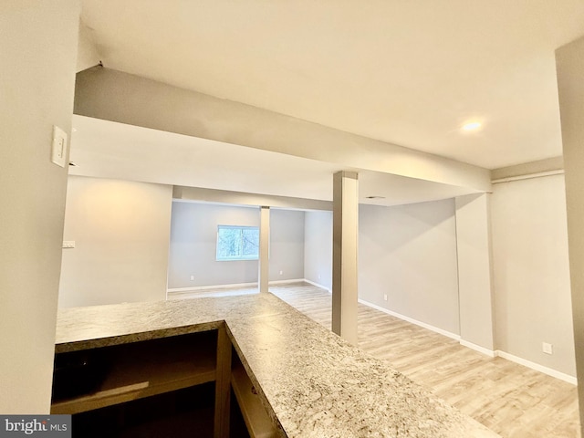 basement with baseboards and light wood-style floors