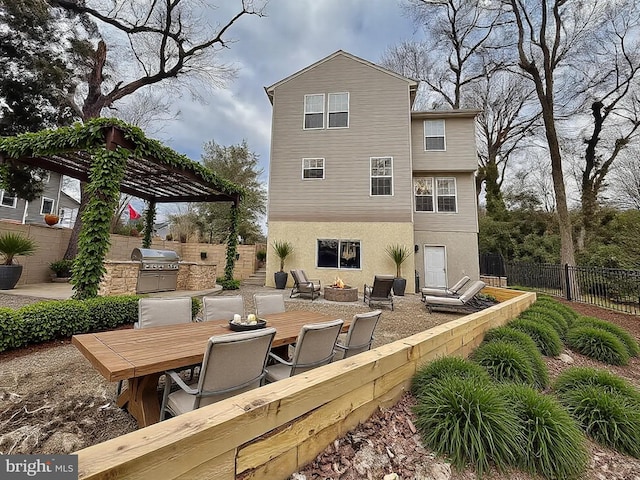 back of house with an outdoor kitchen, an outdoor fire pit, a fenced backyard, and stucco siding