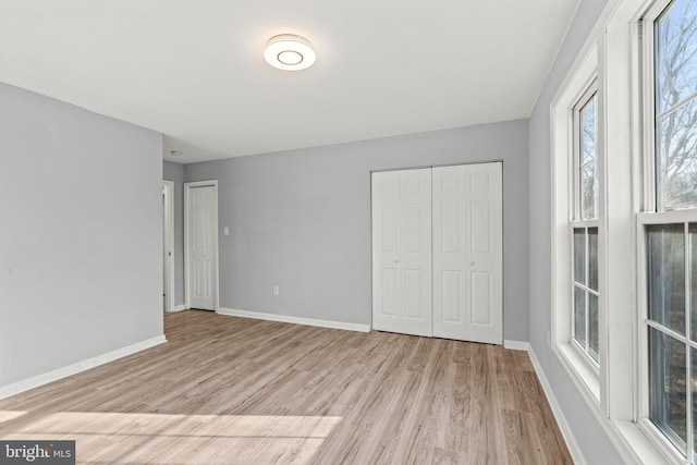 unfurnished bedroom with light wood finished floors, baseboards, and multiple closets