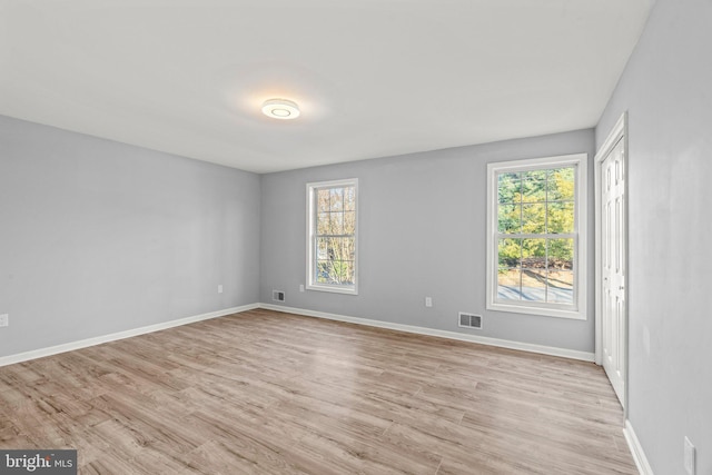 spare room with light wood-style floors, visible vents, and baseboards