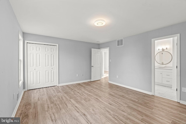 unfurnished bedroom with visible vents, light wood-style flooring, ensuite bathroom, and baseboards