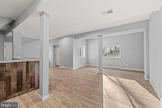 unfurnished living room featuring visible vents, baseboards, and light wood-style flooring