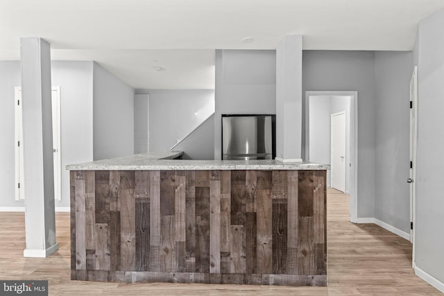 kitchen with baseboards, light wood-type flooring, and stainless steel refrigerator