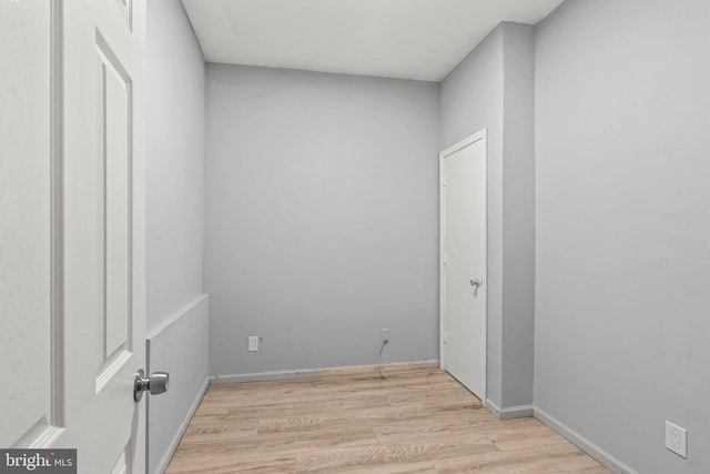 unfurnished room with baseboards and light wood-type flooring