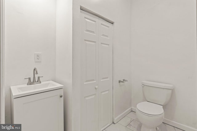 bathroom featuring vanity, toilet, marble finish floor, and a closet