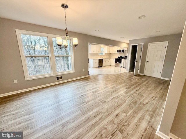 unfurnished dining area featuring visible vents, baseboards, light wood-style flooring, and a chandelier