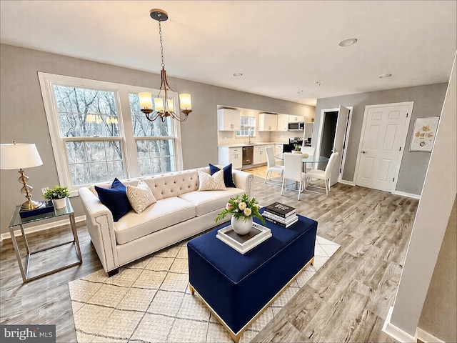 living room featuring baseboards, light wood-style floors, and a chandelier