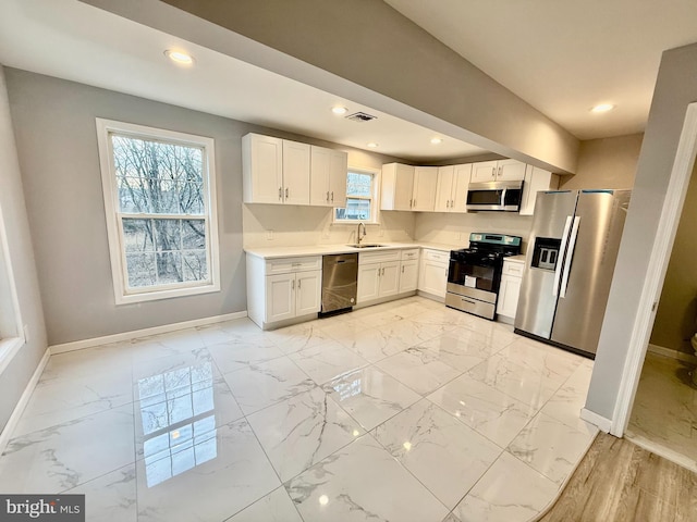 kitchen with visible vents, marble finish floor, appliances with stainless steel finishes, white cabinets, and baseboards