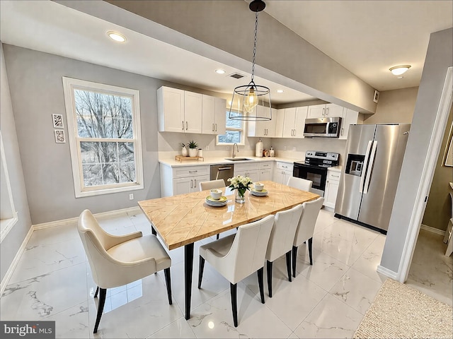 kitchen featuring baseboards, a sink, light countertops, appliances with stainless steel finishes, and marble finish floor