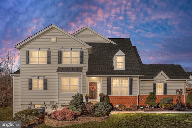 traditional home with brick siding, a shingled roof, and a front yard