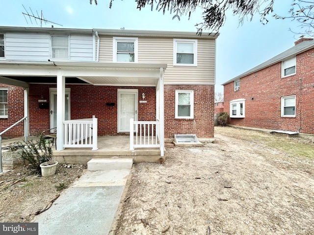 view of property featuring covered porch and brick siding