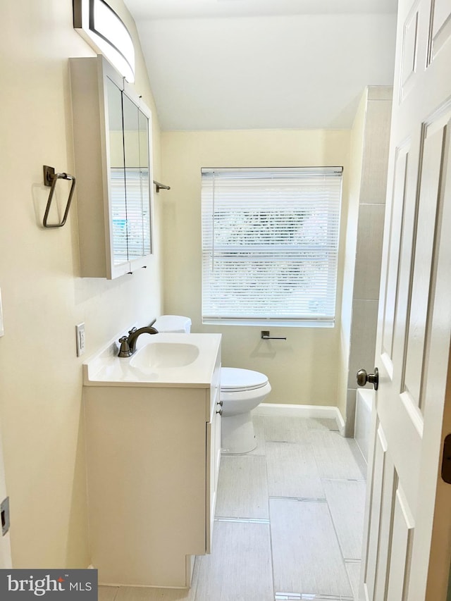 bathroom with toilet, baseboards, vaulted ceiling, and vanity