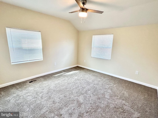 carpeted spare room with a ceiling fan, vaulted ceiling, and baseboards