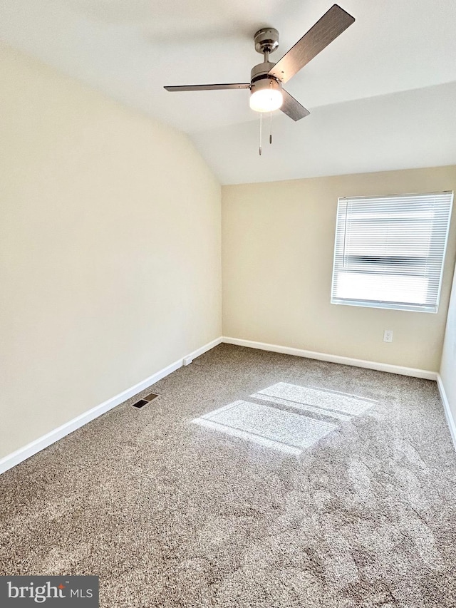 carpeted empty room with vaulted ceiling, ceiling fan, visible vents, and baseboards