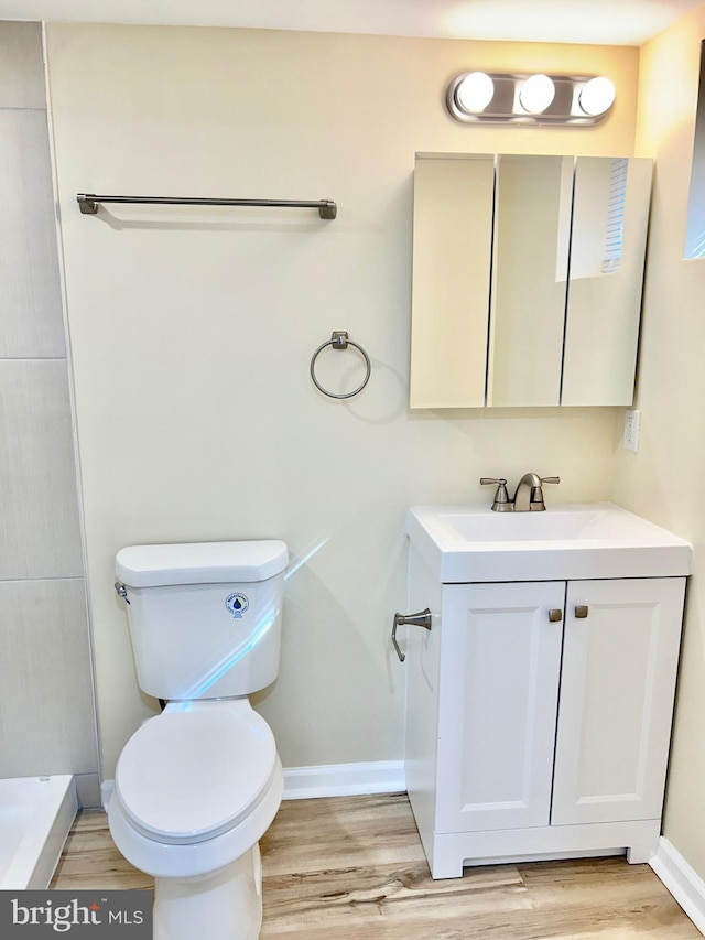 bathroom with vanity, wood finished floors, toilet, and baseboards