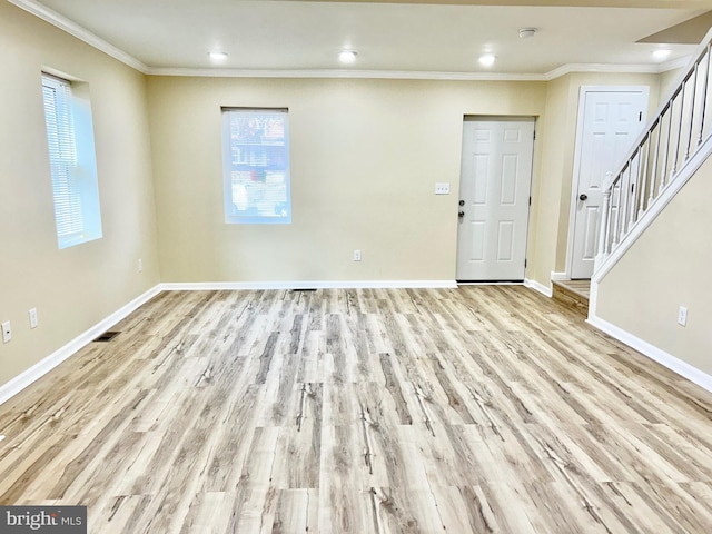 empty room with baseboards, wood finished floors, stairs, and crown molding