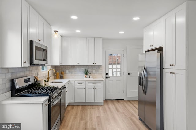 kitchen with white cabinetry, light wood-style flooring, appliances with stainless steel finishes, and a sink