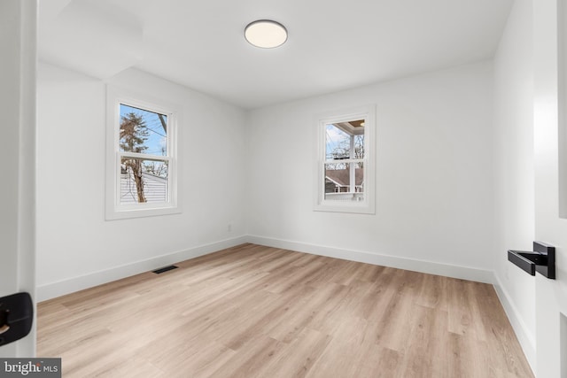 spare room with visible vents, plenty of natural light, light wood finished floors, and baseboards