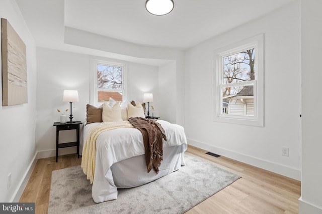 bedroom with light wood-style flooring, multiple windows, and visible vents