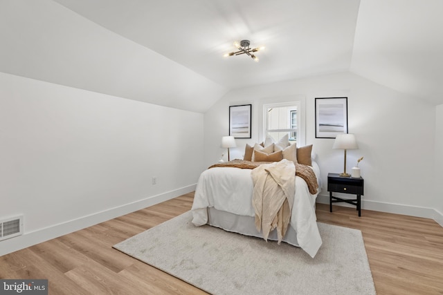 bedroom with lofted ceiling, baseboards, visible vents, and light wood finished floors